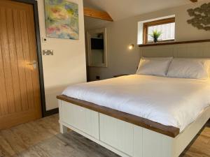 a bedroom with a large white bed with a window at The Cow Shed - Rural Barn Conversion in Little Bytham