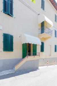 un bâtiment blanc avec des volets verts et un porche dans l'établissement Siena UpTown - Sabrina's Lovely Apartment, à Sienne