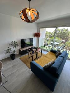 ein Wohnzimmer mit einem blauen Sofa und einem TV in der Unterkunft Appartement au bord de mer in Saint-Brevin-les-Pins