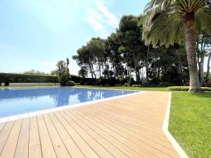 uma piscina com um deque de madeira ao lado de uma palmeira em LuxuryCambrils Resort&Spa em Cambrils