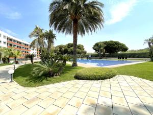 un complexe avec un palmier et une piscine dans l'établissement LuxuryCambrils Resort&Spa, à Cambrils