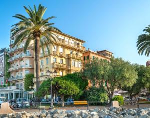 un grand bâtiment avec un palmier en face dans l'établissement Hotel Rosa Bianca, à Rapallo