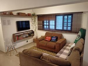 ein Wohnzimmer mit 2 Sofas und einem TV in der Unterkunft CASA SERENA - Piscina, Wi-fi e Conforto bem pertinho da praia in Itanhaém