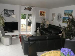 sala de estar con sofá de cuero negro y TV en appt de 70m2, a 4 km la plage, en Saint-Paul-de-Vence