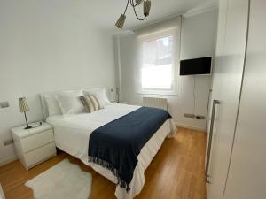 a white bedroom with a large bed and a window at Apartamento Lea in Bilbao
