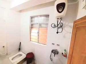 biała łazienka z toaletą i oknem w obiekcie International Youth Hostel and Homestay Kurseong Bazar w mieście Kurseong