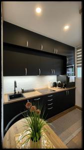 a kitchen with black cabinets and a sink and a table at Good Knight Apartman in Szeged
