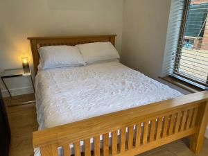 a wooden bed in a bedroom with a window at Stansted Airport Luxury Annexe with Parking. in Birchanger