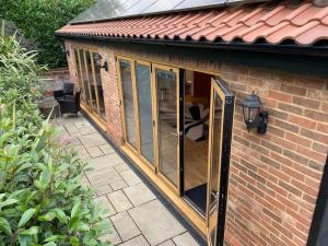 a greenhouse with glass doors on a brick building at Stansted Airport Luxury Annexe with Parking. in Birchanger