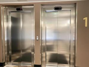 twee metalen liftdeuren in een gebouw bij Goldfinger saunallinen kaksio merinäköalalla 11 krs in Helsinki