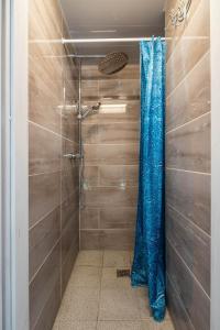 a shower with a blue plastic curtain in a bathroom at Kuren Hostel in Karklė