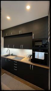 a kitchen with black cabinets and a microwave at Good Knight Apartman in Szeged