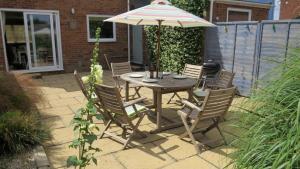 a table and chairs with an umbrella on a patio at Poplars in Aldeburgh