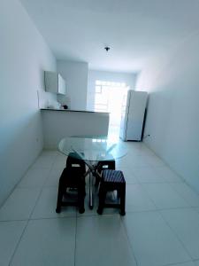 a kitchen with a glass table and two chairs and a refrigerator at Apartamento Mobiliado no Centro da Cidade in Imperatriz