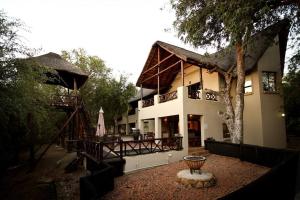 a large white building with a tree in front of it at Eden Safari Country House in Marloth Park