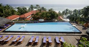 a view of a swimming pool with chairs and the ocean at Gokulam Grand Turtle On The Beach in Kovalam