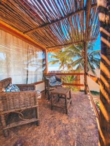 a porch with chairs and a table and a palm tree at Vila do Alto - Beach Homes in Itarema
