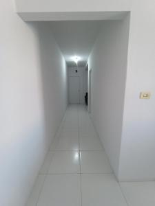 um corredor vazio com paredes brancas e um piso branco em Apartamento Mobiliado no Centro da Cidade em Imperatriz