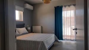 um quarto com uma cama e uma janela com cortinas azuis em Elena Apartments em Kato Daratso