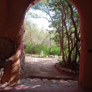 uma arcada numa casa com uma estrada de terra e árvores em Espacio Circular em San Marcos Sierras