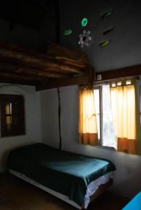 um quarto com uma cama verde e 2 janelas em Espacio Circular em San Marcos Sierras