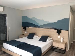 una camera da letto con un grande letto con montagne sul muro di Hostel S. Miguel FitNCare a Guarda