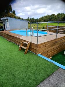 a large wooden deck with a swimming pool at Bungalow charmant à Château Gaillard avec piscine partagée in Le Moule