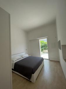 a white bedroom with a bed and a window at SALENTO AT HOME in Nardò