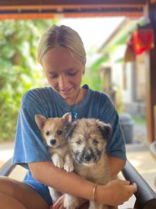 Eine Frau, die einen Hund und einen kleinen Hund hält. in der Unterkunft Lembongan Hostel in Nusa Lembongan