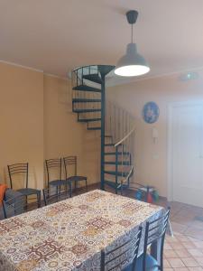 a dining room with a table and a spiral staircase at CASA VACANZA DEL SOLE in Milo