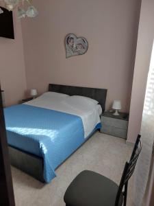 een slaapkamer met een bed met een blauwe deken en een stoel bij CASA VACANZA DEL SOLE in Milo