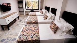 a room with three beds in a room at Hotel Arisha Cali in Cali