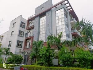 um edifício alto com palmeiras em frente em The Grand Suite-70 em Noida