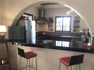 eine Küche mit einer Theke und 2 Hockern in einem Zimmer in der Unterkunft VILLA ALWAN BARAKA - Sans vis à vis, Piscine chauffée, Hammam, Personnel in Essaouira + 56 Fotos