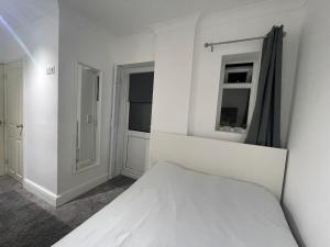 a white bedroom with a bed and a window at Greenwich Room in London