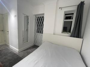 a white bedroom with a bed and a window at Greenwich Room in London