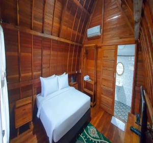 a bedroom with a white bed in a wooden room at Palma Beach Resort in Padangnegeri