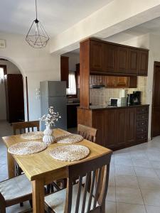 a kitchen with a wooden table with chairs and a refrigerator at The 3M in Kala Nera