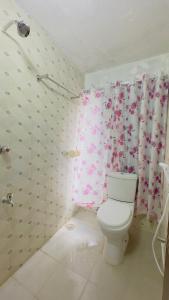 a bathroom with a toilet and a pink shower curtain at Hotel Rose Haven Residential in Dhaka