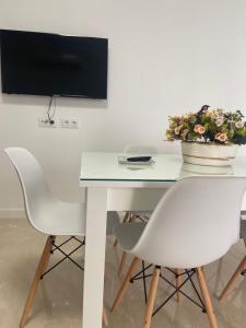 mesa blanca con 2 sillas y TV en la pared en VIVIENDA RURAL EL PROGRESO, en Carchelejo