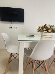 a white table with two chairs and a tv on a wall at VIVIENDA RURAL EL PROGRESO in Carchelejo