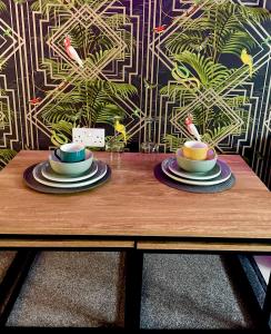a wooden table with two cups and plates on it at Vibrant & Modern studio apartment in Birmingham in Birmingham