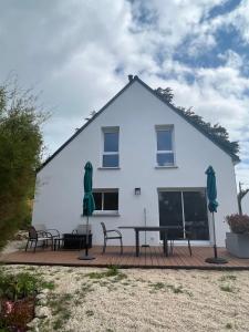 a white house with tables and chairs on a deck at Maison Tamaris avec jardin et clos in Quiberon