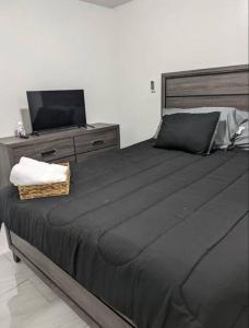 a bedroom with a large black bed and a television at Family-Home-Workplace-Peace in Arecibo