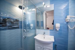 een blauwe badkamer met een wastafel en een douche bij Pensiunea La Gura Portitei - Jurilovca in Jurilovca