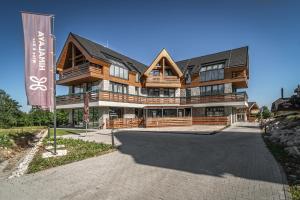 a large wooden building with a flag in front of it at TATRA SUITES Vila HIMALAYA in Tatranská Lomnica