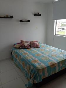 a bed in a white room with a bedspread on it at Apto Agradable y Fresco en Conjunto Cerrado Decimo Piso in Neiva