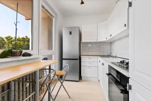 a kitchen with white cabinets and a stainless steel refrigerator at Apartment w Netflix, Coffee or Tea & Parking in Trnávka
