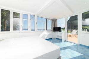 a white bedroom with a bed and a television at Eden sul Mare in Amalfi