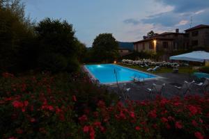 a swimming pool in a yard with chairs and flowers at Villa Milesi in Franciacorta in Erbusco